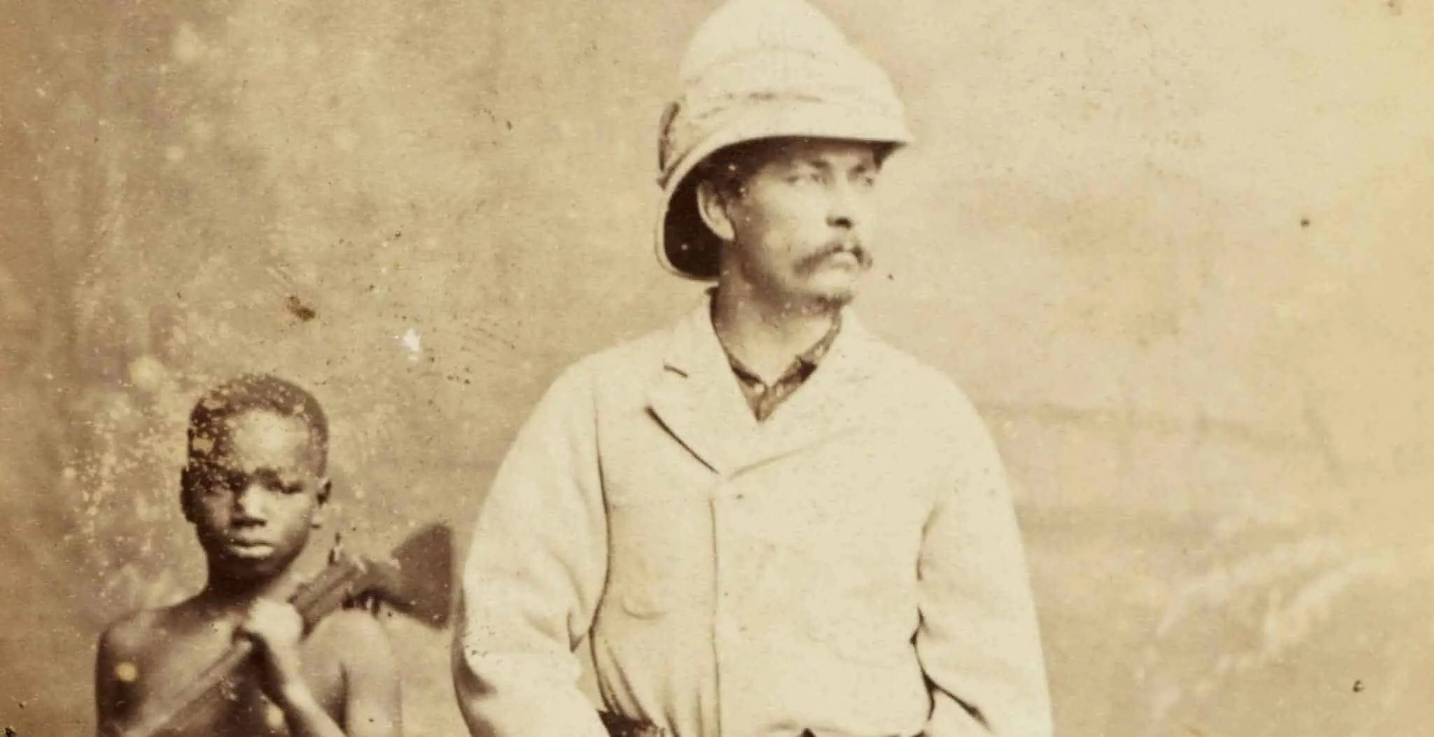 Photograph of Henry Morton Stanley in pith helmet, accompanied by black child